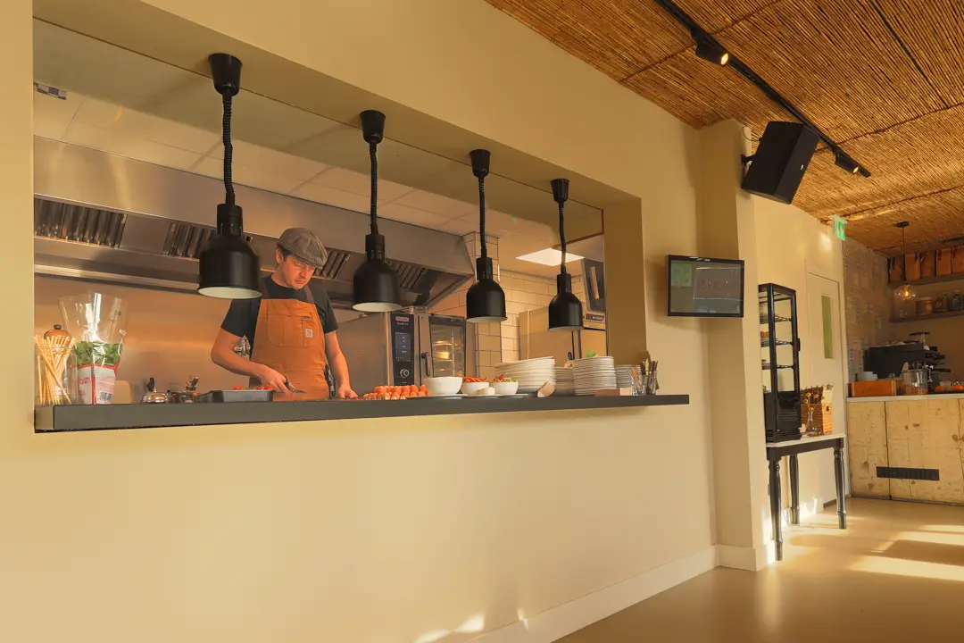 Open keuken met doorgeefluik en warmhoudlampen, waar een kok aan het werk is