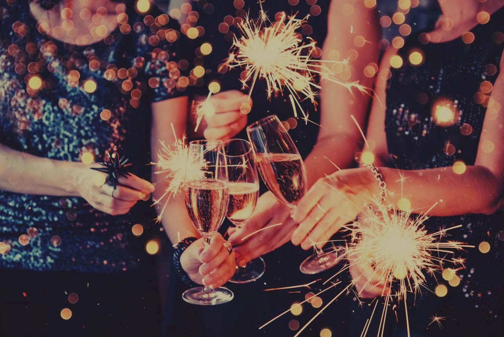 Mensen in glitterkleding proosten met glazen bubbels tussen brandende sterretjes